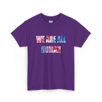 Purple crew neck T-shirt with ‘WE ARE ALL HUMAN’ across the chest in pink and blue watercolor-style lettering, front view.