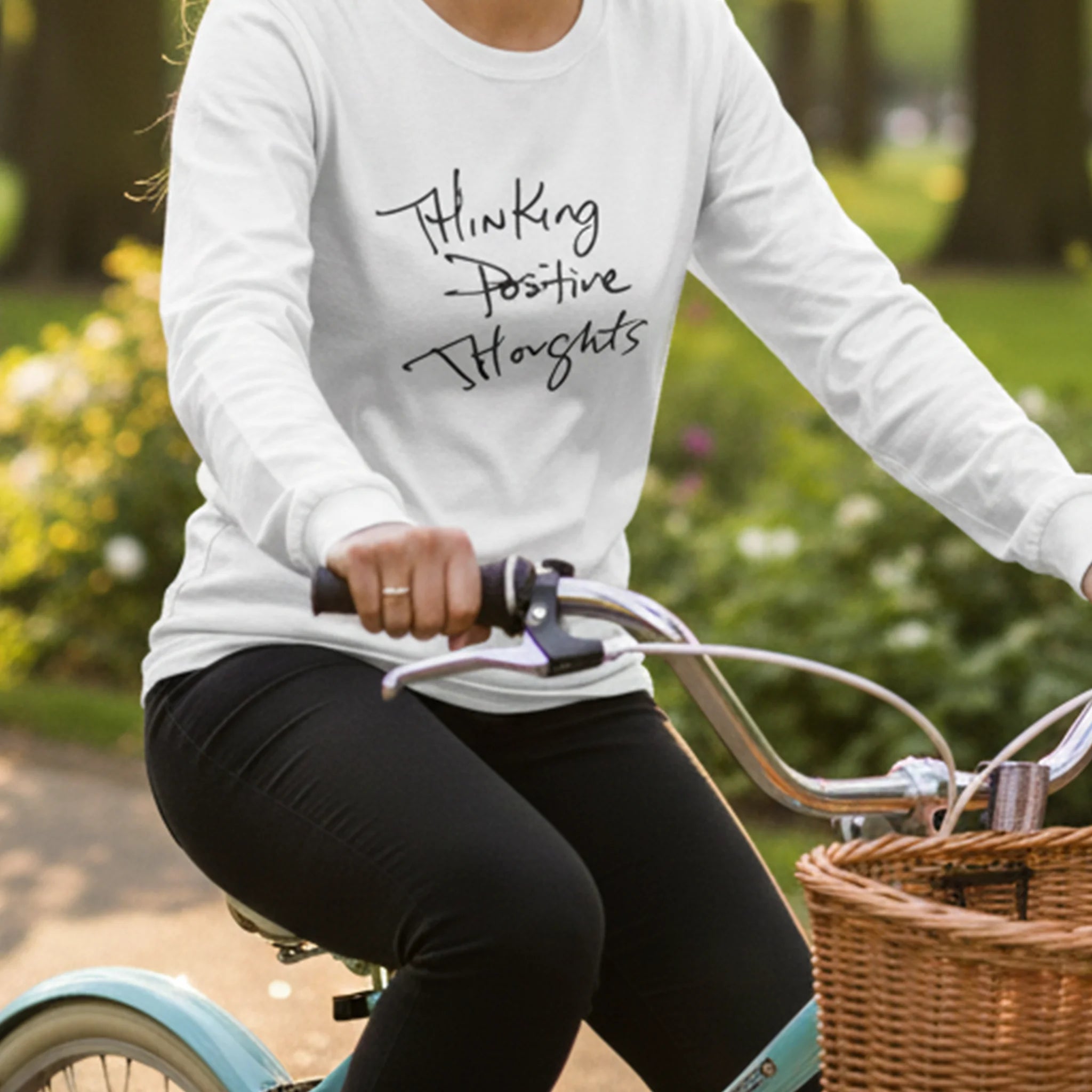 White Thinking Positive Thoughts long sleeve tee, outdoor bike ride lifestyle front view.